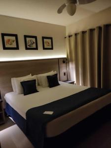 1 dormitorio con 1 cama grande con almohadas blancas y negras en Summit Beach Hotel Boiçucanga, en Boicucanga