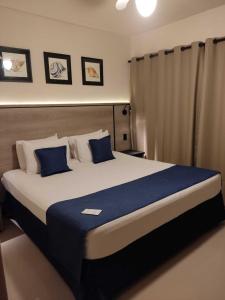 a bedroom with a large bed with blue pillows at Summit Beach Hotel Boiçucanga in Boicucanga