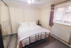 a bedroom with a bed with white sheets and a window at 1 Bedroom Apartment close to Slough Train Station in Slough