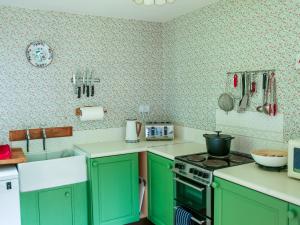 a kitchen with green cabinets and a stove top oven at Henllys Lodge in Velindre-farchog