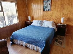 1 dormitorio con 1 cama azul y 2 mesitas de noche en Hostal Reymar, en Puerto Natales