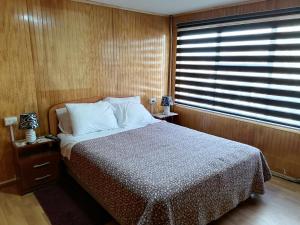 a bedroom with a bed and a large window at Hostal Reymar in Puerto Natales