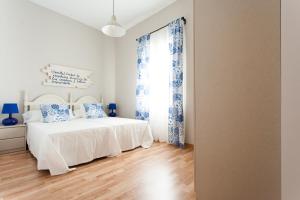 Apartamentos Diaber Laraña في إشبيلية: غرفة نوم بيضاء بها سرير ونافذة