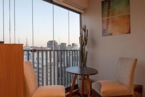 Habitación con mesa, sillas y ventana grande. en 360 Suítes Facto Paulista - Apartamentos mobiliados, en São Paulo