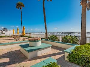 Sunrise & Beach View - Daytona Beach Resort في دايتونا بيتش: جلسة فيها نخيل والشاطئ في الخلف