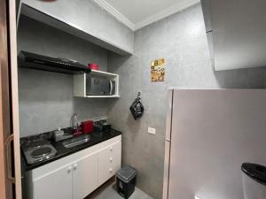 uma pequena cozinha com um lavatório e um frigorífico em Kitnet Premium Canto do Forte - Praia Grande na Praia Grande