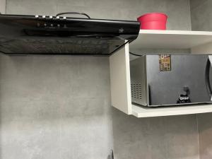 a microwave in a kitchen with a red cup at Kitnet Premium Canto do Forte - Praia Grande in Praia Grande
