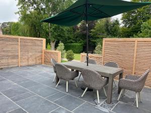 einen Tisch und Stühle mit Sonnenschirm auf einer Terrasse in der Unterkunft Linhay Cottages in Box