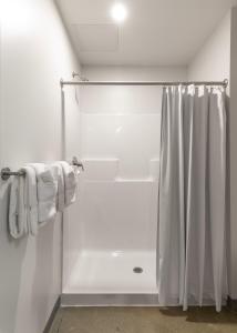 a bathroom with a shower with a white shower curtain at The Warehouse Hotel at Champion Mill in Hamilton