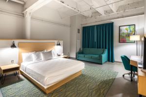 a hotel room with a bed and a blue couch at The Warehouse Hotel at Champion Mill in Hamilton