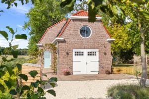a small red brick building with white doors at Beach & Forest Retreat -Domburg- in Oostkapelle