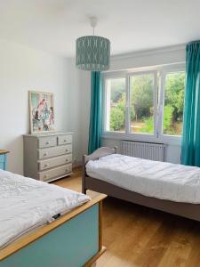 twee bedden in een slaapkamer met blauwe gordijnen bij Entre mer et falaises in Équihen-Plage