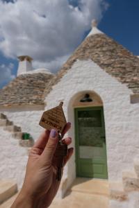 a person holding a small house key in front of a building at Dimora Iconica in Locorotondo