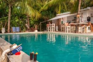 a swimming pool with a house and palm trees at Sharazad Boutique Hotel in Jambiani