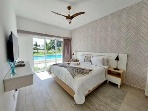 a bedroom with a large bed and a television at Spectacular Apto Pool Golf View in Hard Rock Golf in Punta Cana