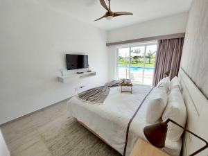 a bedroom with a bed and a tv and a window at Spectacular Apto Pool Golf View in Hard Rock Golf in Punta Cana