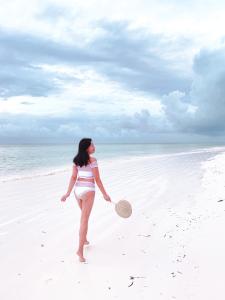 a woman standing on the beach with a racket at Sharazad Oasis Retreat in Jambiani