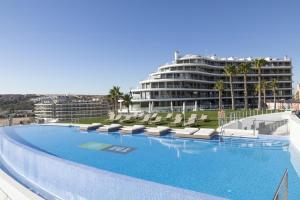 a large swimming pool with lounge chairs and a large building at Infinity View SNB in Arenales del Sol