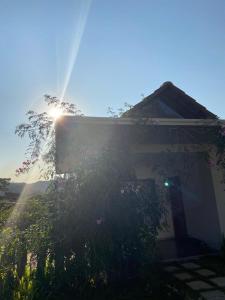une maison où le soleil brille derrière un arbre dans l'établissement Canto das Pedras Flats, à Caparaó Velho