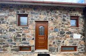 ein Steingebäude mit einer Holztür und vier Fenstern in der Unterkunft Casa da Barriada II in Bragança