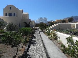 a garden in front of a house with trees and buildings at Dagris Villa Studios in Kamari