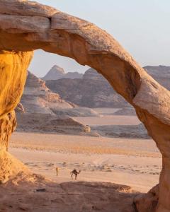 an arch in the desert with two people and a camel at Star Wars Wadi Rum in Wadi Rum
