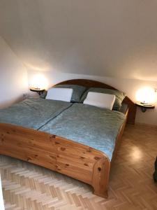a bedroom with a wooden bed with two white chairs at Klopeinerperle in Peratschitzen