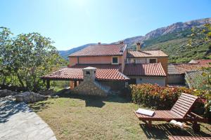 a house with a yard with two chairs in front of it at Holiday house with a swimming pool Draga Bascanska, Krk - 19204 in Draga Bašćanska