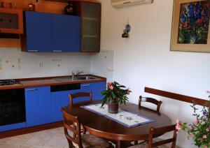 eine Küche mit blauen Schränken und einem Tisch mit Stühlen in der Unterkunft Apartments by the sea Drvenik Veliki, Drvenik - 19229 in Drvenik Veli
