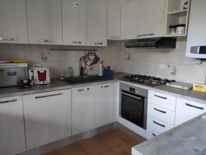 uma cozinha com armários brancos e um forno com placa de fogão em Casa panoramica em Attimis