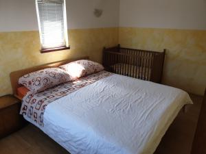 ein Bett mit zwei Kissen und einem Kinderbett in einem Schlafzimmer in der Unterkunft Apartments by the sea Tkon, Pasman - 19024 in Tkon