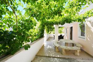 a table and a bench on a patio with trees at Apartments by the sea Tkon, Pasman - 19024 in Tkon