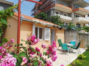 a house with a table and chairs and flowers at Apartments with a parking space Seget Vranjica, Trogir - 19022 in Seget Donji