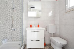 a white bathroom with a toilet and a shower at Seaside house for families with children Zavalatica, Korcula - 19045 in Čara