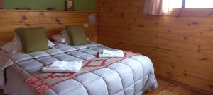 een slaapkamer met een wit bed in een houten muur bij La Ribera - Sepúlveda 191 in El Chalten