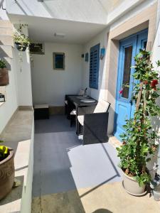 eine Terrasse mit einem Tisch, Stühlen und einer blauen Tür in der Unterkunft Apartments by the sea Veli Losinj, Losinj - 19196 in Veli Lošinj