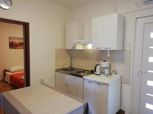 eine kleine Küche mit weißen Schränken und einer Spüle in der Unterkunft Apartments by the sea Nin, Zadar - 19103 in Nin