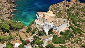 a large building on a mountain next to the ocean at Elafonisi Vacation Blue Apartment in Agios Padeleimon