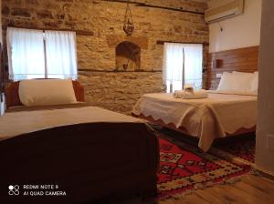 Guest House Salaria في غيروكاستر: غرفة نوم بسريرين وجدار حجري