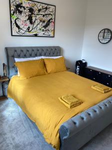 un letto con lenzuola gialle e cuscini gialli in una camera da letto di Stylish 2 Bed Apt, 2 Minute Walk From The Beach. a Sheringham