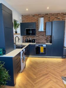 a kitchen with blue cabinets and a brick wall at Stylish 2 Bed Apt, 2 Minute Walk From The Beach. in Sheringham