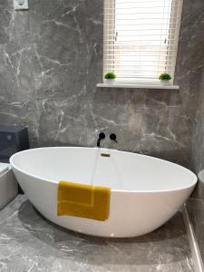 a white bath tub in a bathroom with a window at Stylish 2 Bed Apt, 2 Minute Walk From The Beach. in Sheringham