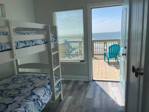a bedroom with bunk beds and a balcony with the ocean at Surfside Beachfront Luxe in Surfside Beach