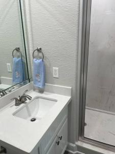 a bathroom with a sink and a mirror and a shower at Surfside Beachfront Luxe in Surfside Beach