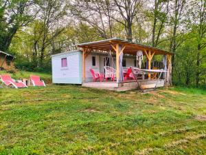 a house with a gazebo and chairs in a yard at restyled bohemian mobil home la vie en rose in Montcléra