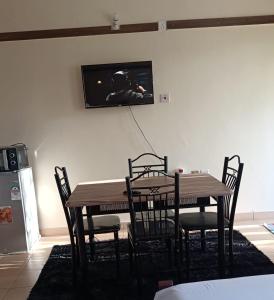 a dining room table with chairs and a tv on a wall at Mkombodzi Global Homes in Mtwapa