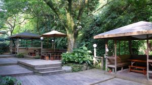 a wooden deck with tables and umbrellas and trees at Silk Valley SPA Resort in Taipei