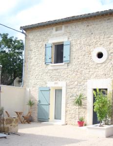 a stone house with blue doors and windows at Maison 1862 - Hébergements d'hôte in Orsan