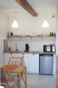 a kitchen with white cabinets and a table and a sink at Maison 1862 - Hébergements d'hôte in Orsan