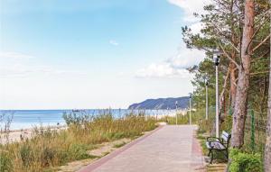 a sidewalk next to the beach with a bench at Stunning Apartment In Miedzyzdroje With 2 Bedrooms And Wifi in Międzyzdroje